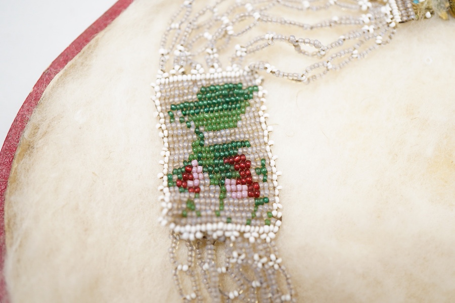 A glass bead necklace, early 19th century, intricately composed of woven glass beads depicting panels of butterflies and flowers, together with early 20th century correspondence from the Victorian & Albert Museum discuss